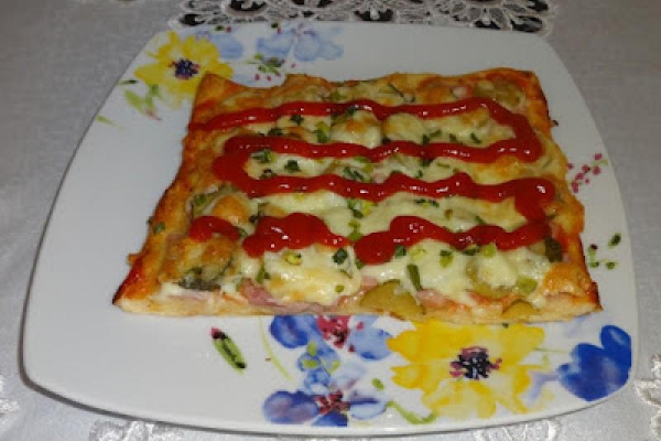 Pizza z szynką, ogórkiem marynowanym i serem.