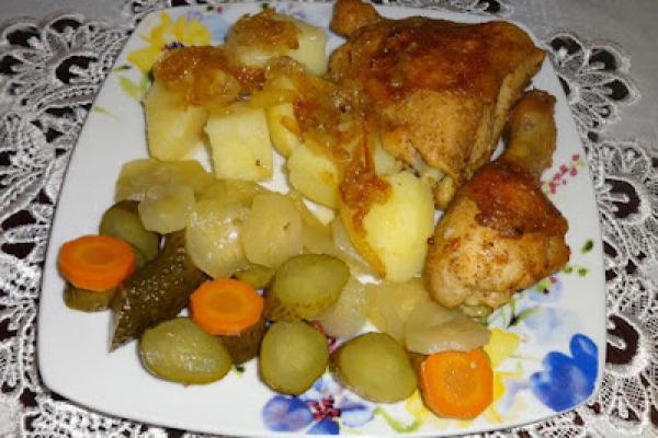 Smażone części kurczaka, ziemniaki i sałatka z ogórków.