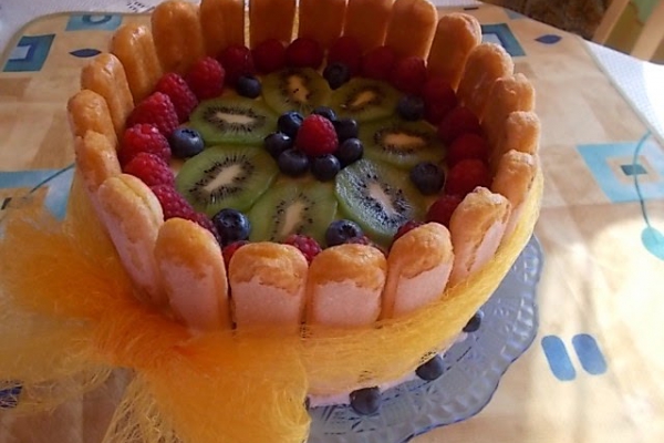 Tort z bitą śmietaną i owocami na biszkoptach.